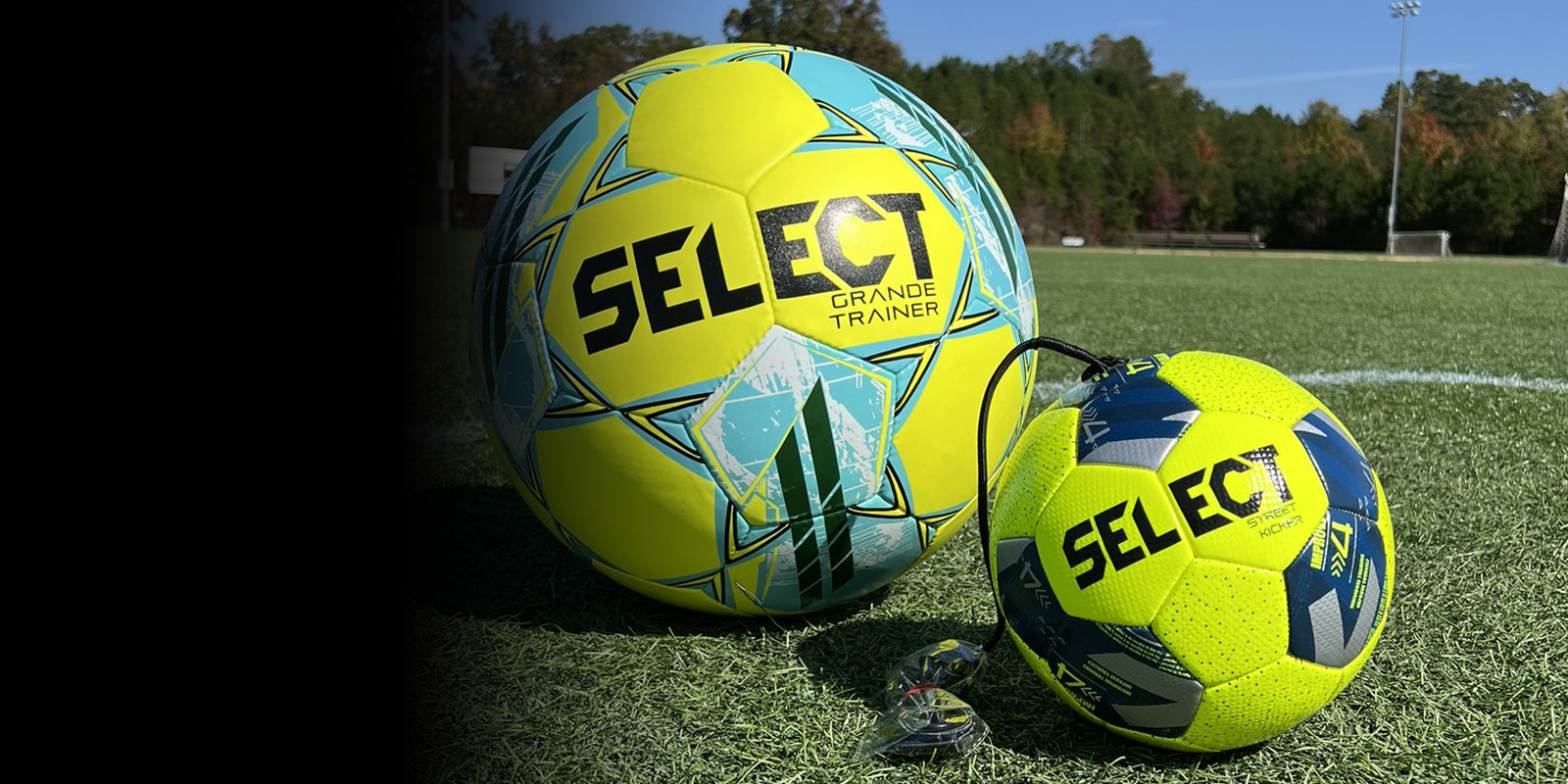 A giant yellow soccer ball and a yellow and navy soccer ball on a soccer field. Fade from black to transparent from left to right