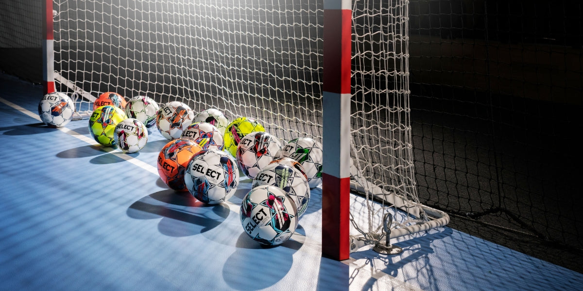 A variety of SELECT futsal balls in a futsal goal