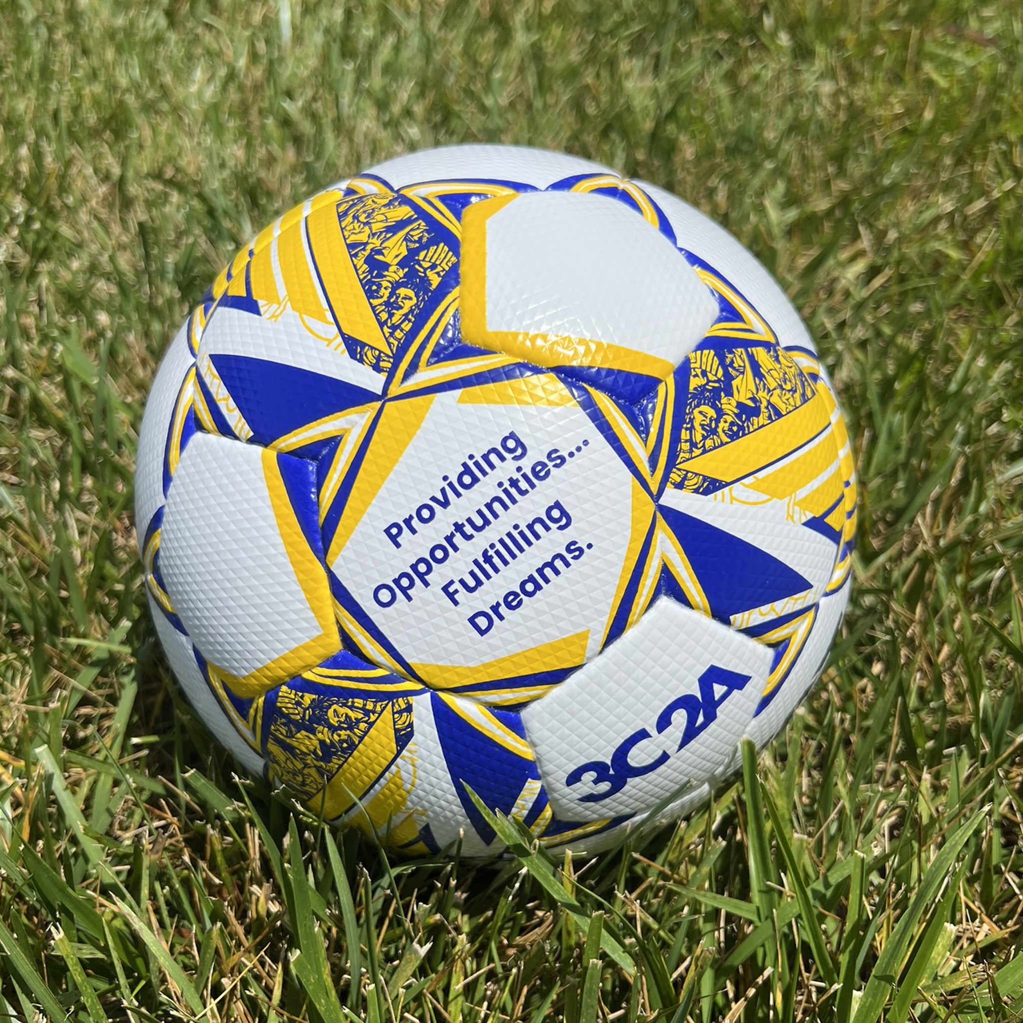 White soccer ball with blue and yellow accents and 'Select' branding on a grass field