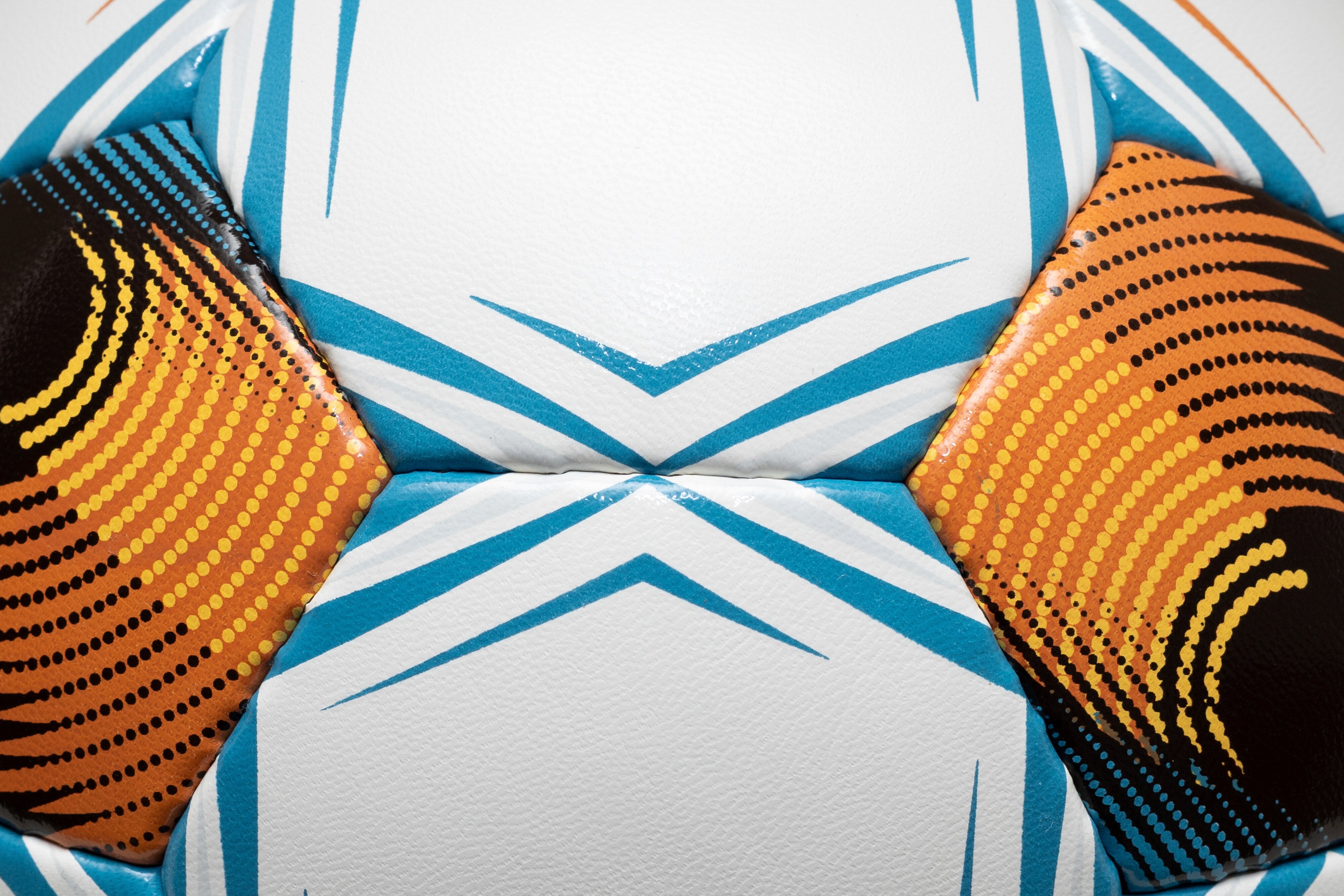 Closeup of Planet NFHS v26 soccer ball, white surface with blue, orange and black panel details.
