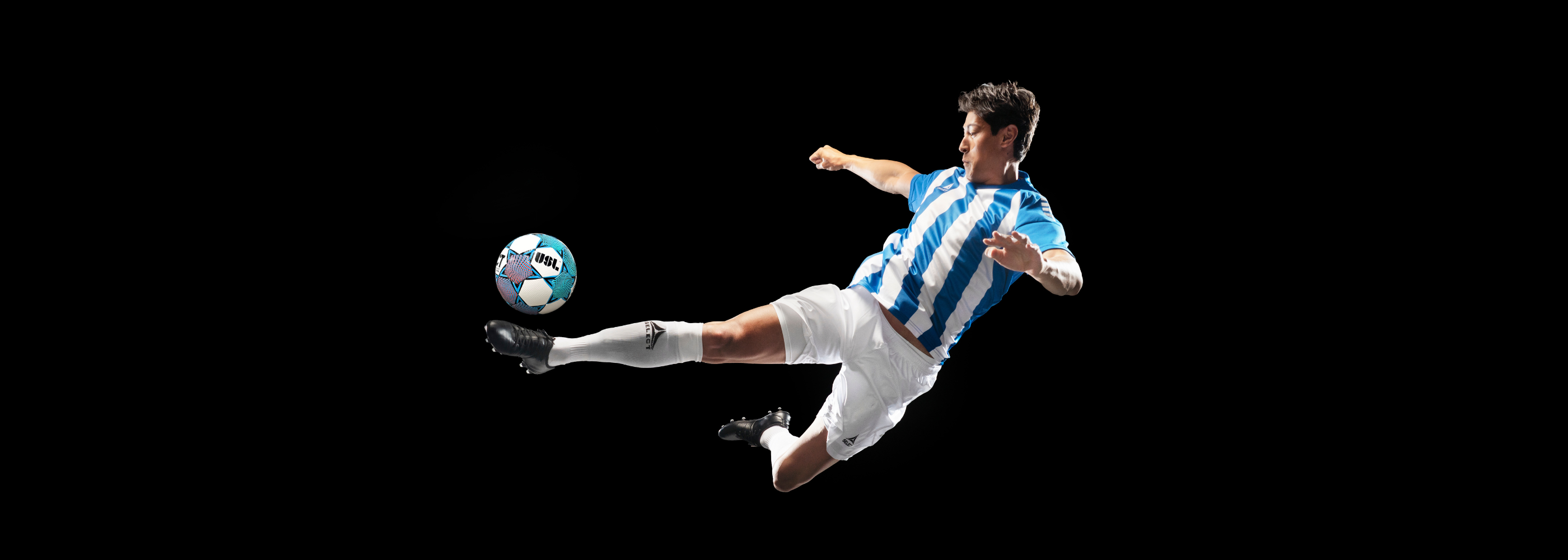 Soccer player in mid-air kicking a soccer ball on a black background
