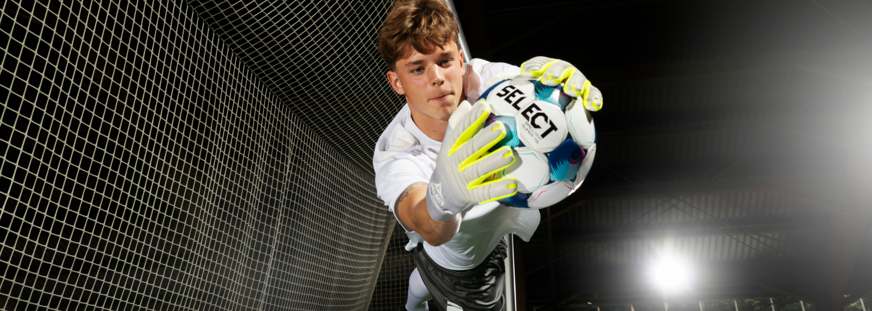 Goalkeeper diving and catching ball. Wearing new 2026 gloves