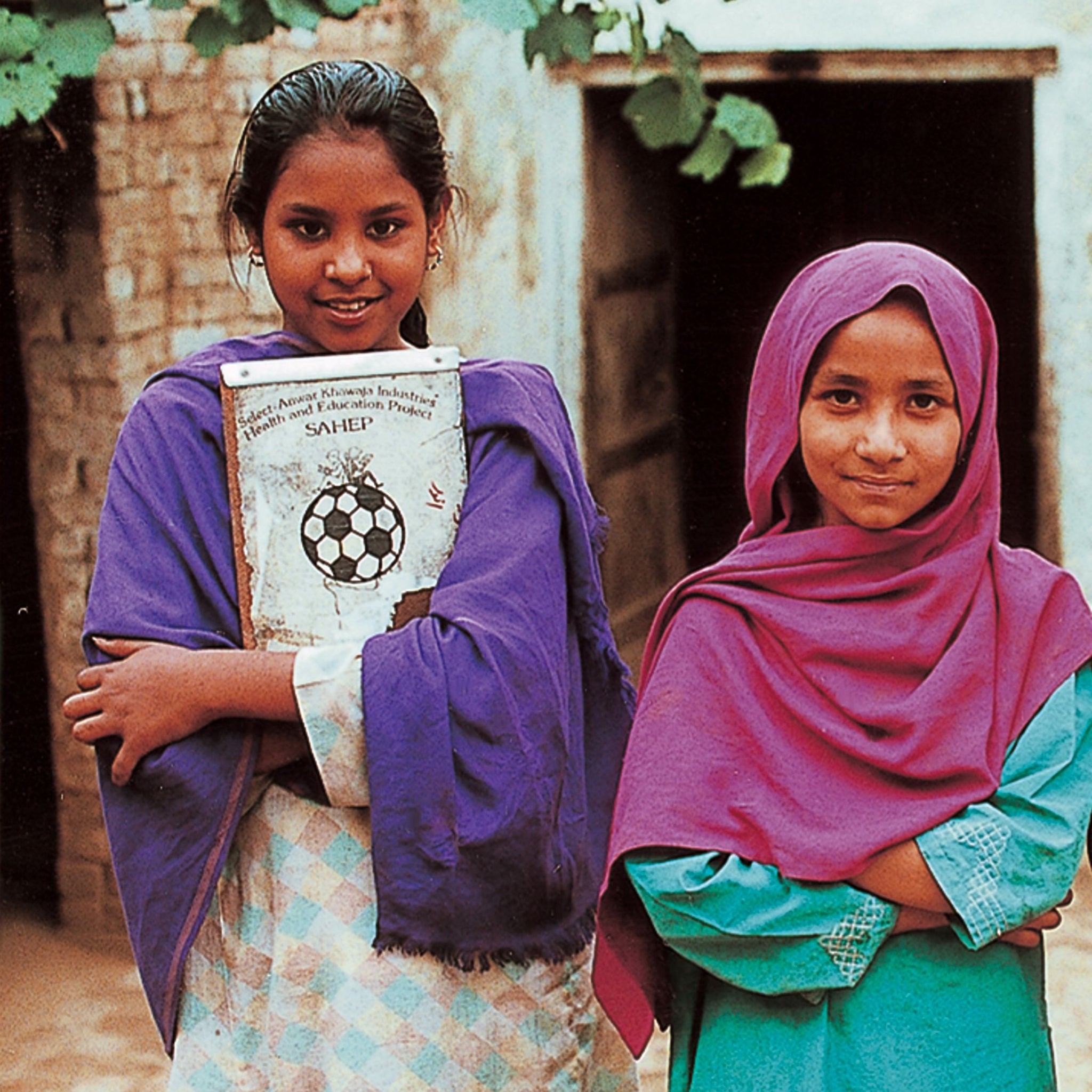 Two girls with one holding a Select Anwar Khawaja Industries Health & education program sign highlighting Select's CSR